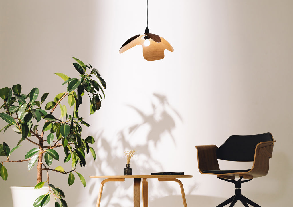 Modern interior with a plant, small table, and chair under a pendant light.