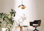 Modern interior with a plant, small table, and chair under a pendant light.