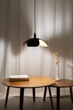 Modern wooden pendant light over a wooden table with minimalist decor.