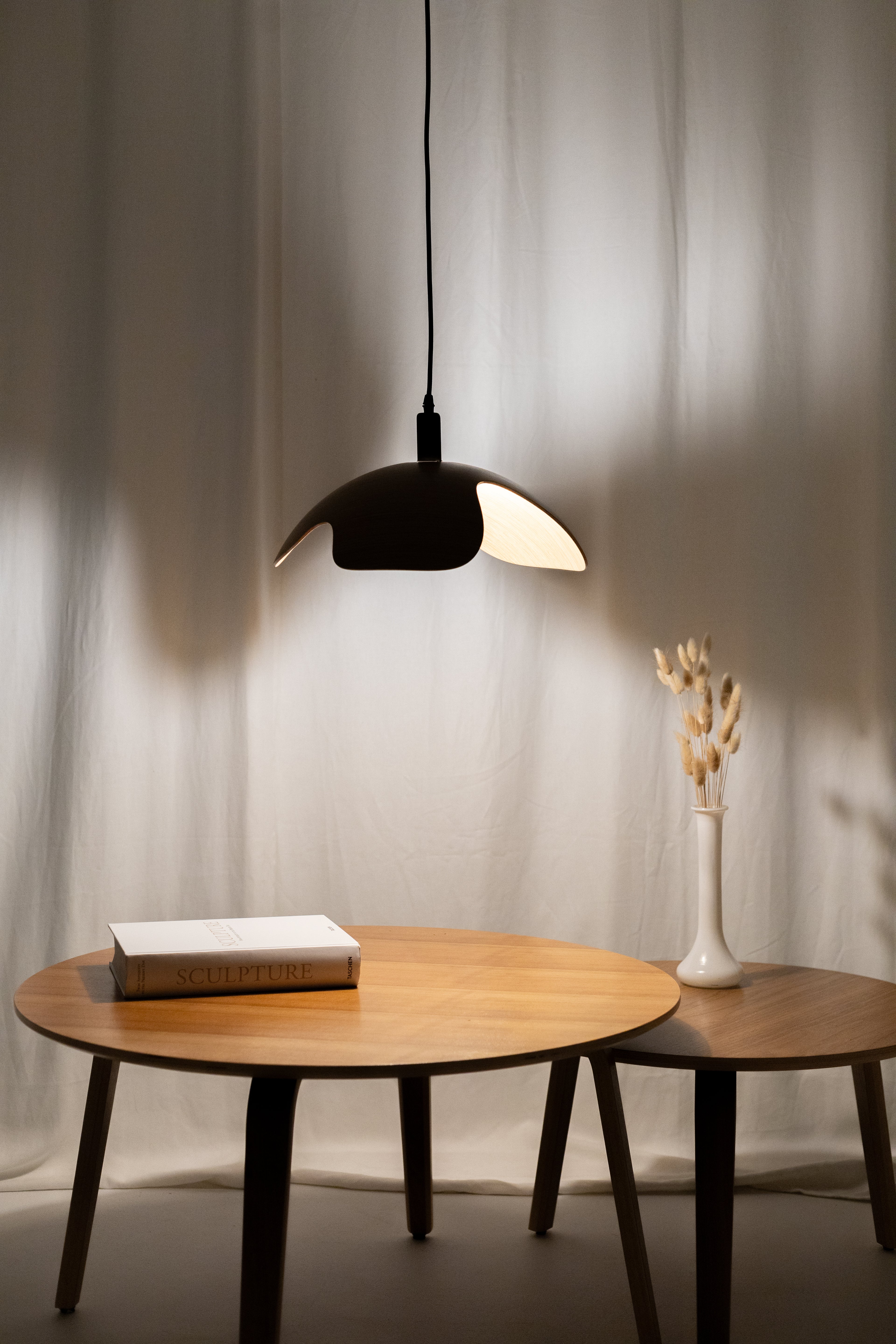 Modern wooden pendant light over a wooden table with minimalist decor.