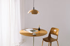 Small round wooden table with a chair under a pendant light in a minimalistic room.