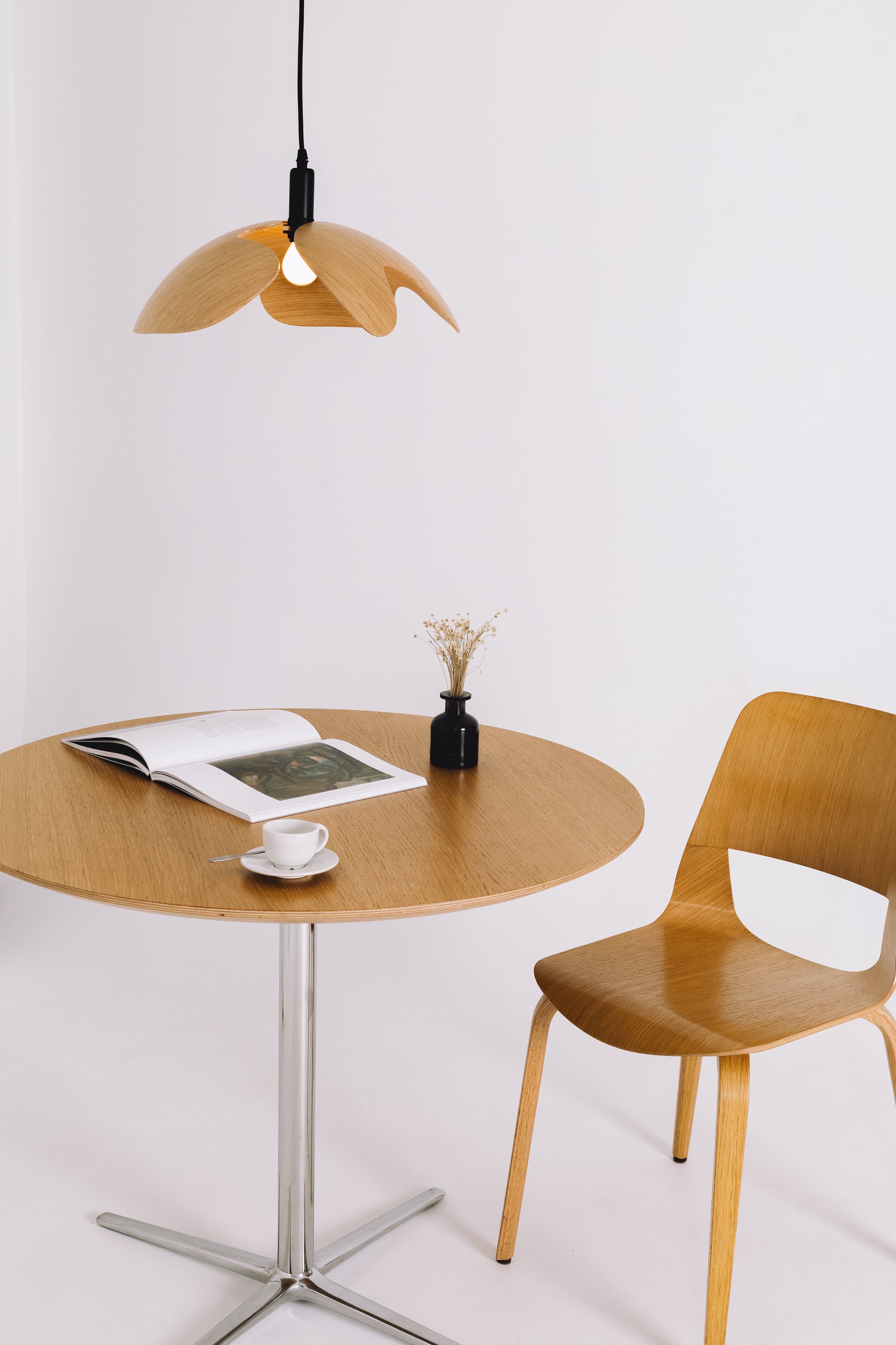 Wooden table with chair and pendant light against a white background