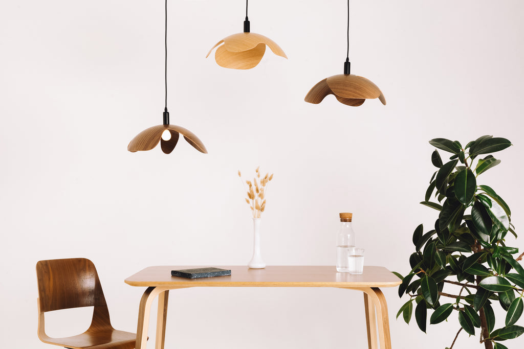 Modern dining area with wooden table, chairs, and pendant lights against a white wall.